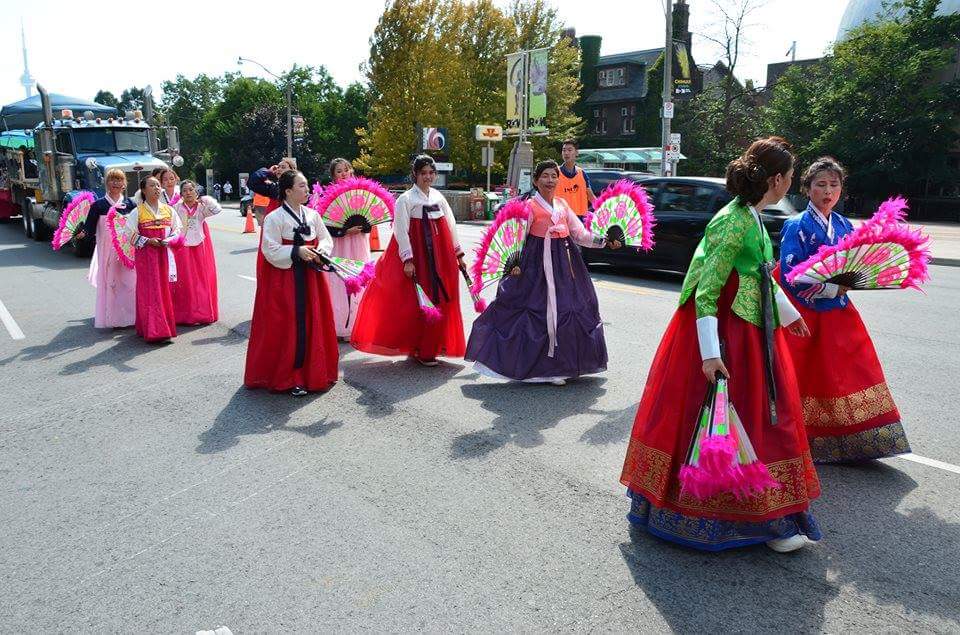 A group of women in traditional korean costumes are marching down a street