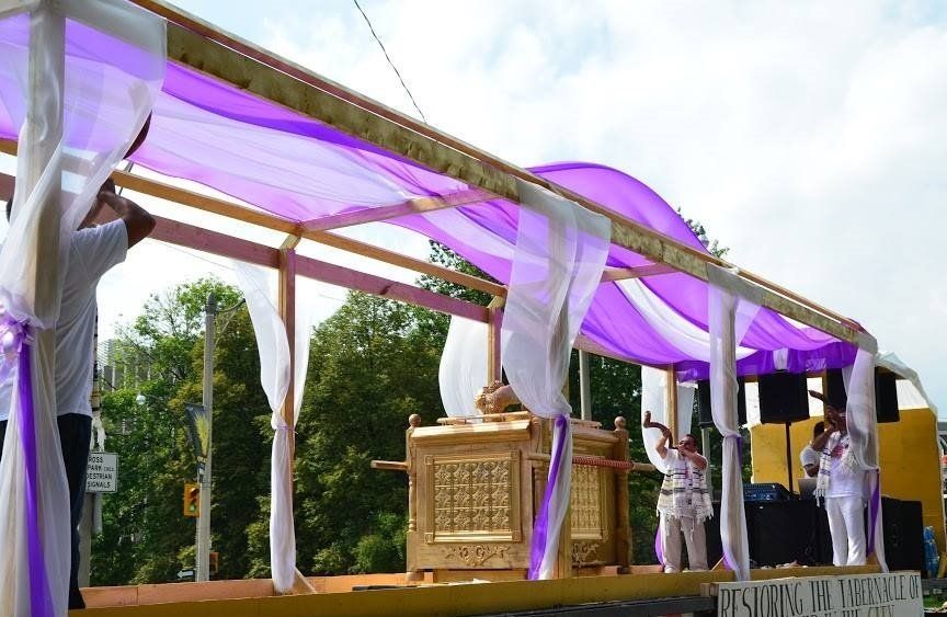 A purple and white canopy is being built on a stage