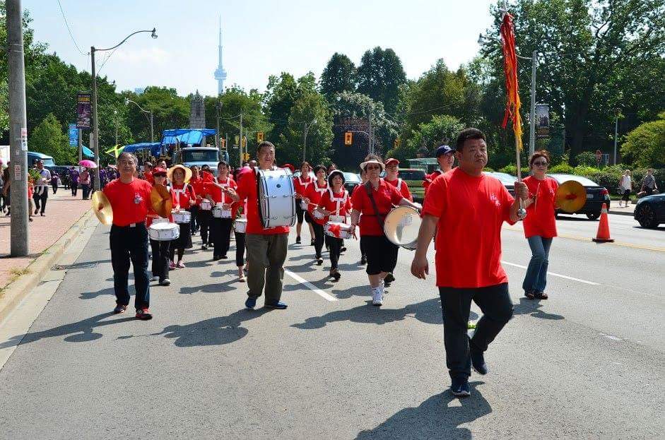 A group of people in red shirts march down a street