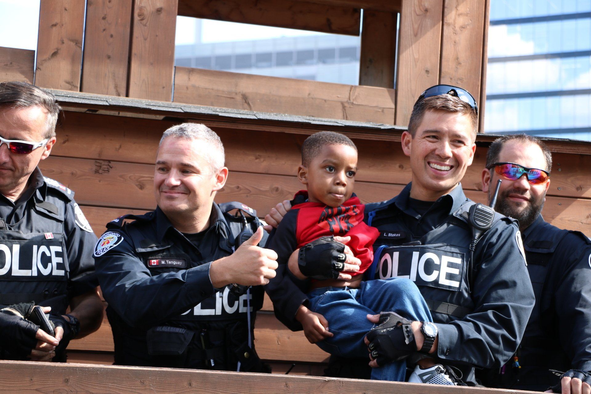 A group of police officers are holding a baby and giving a thumbs up.
