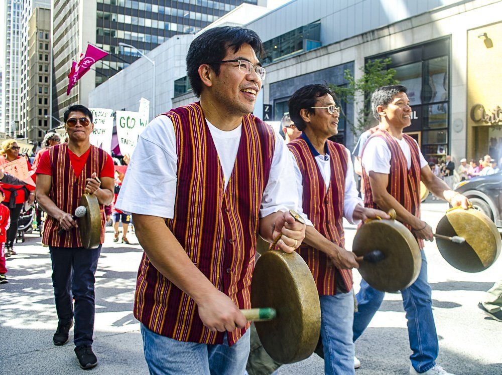A group of men are marching down a street holding drums.