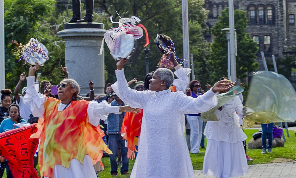 A group of people are dancing in a park.