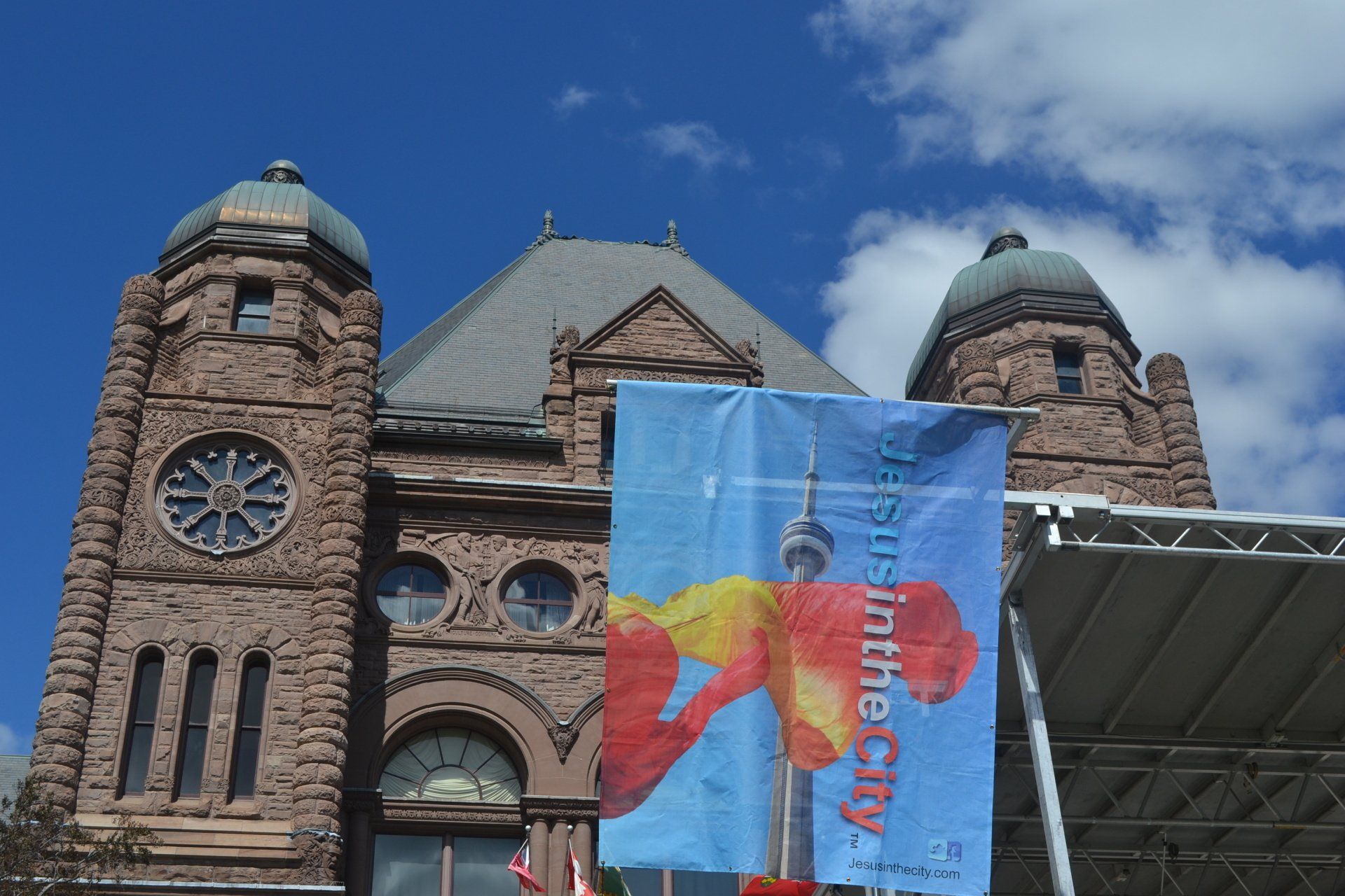 A large brick building with a clock tower and a banner that says life in the city