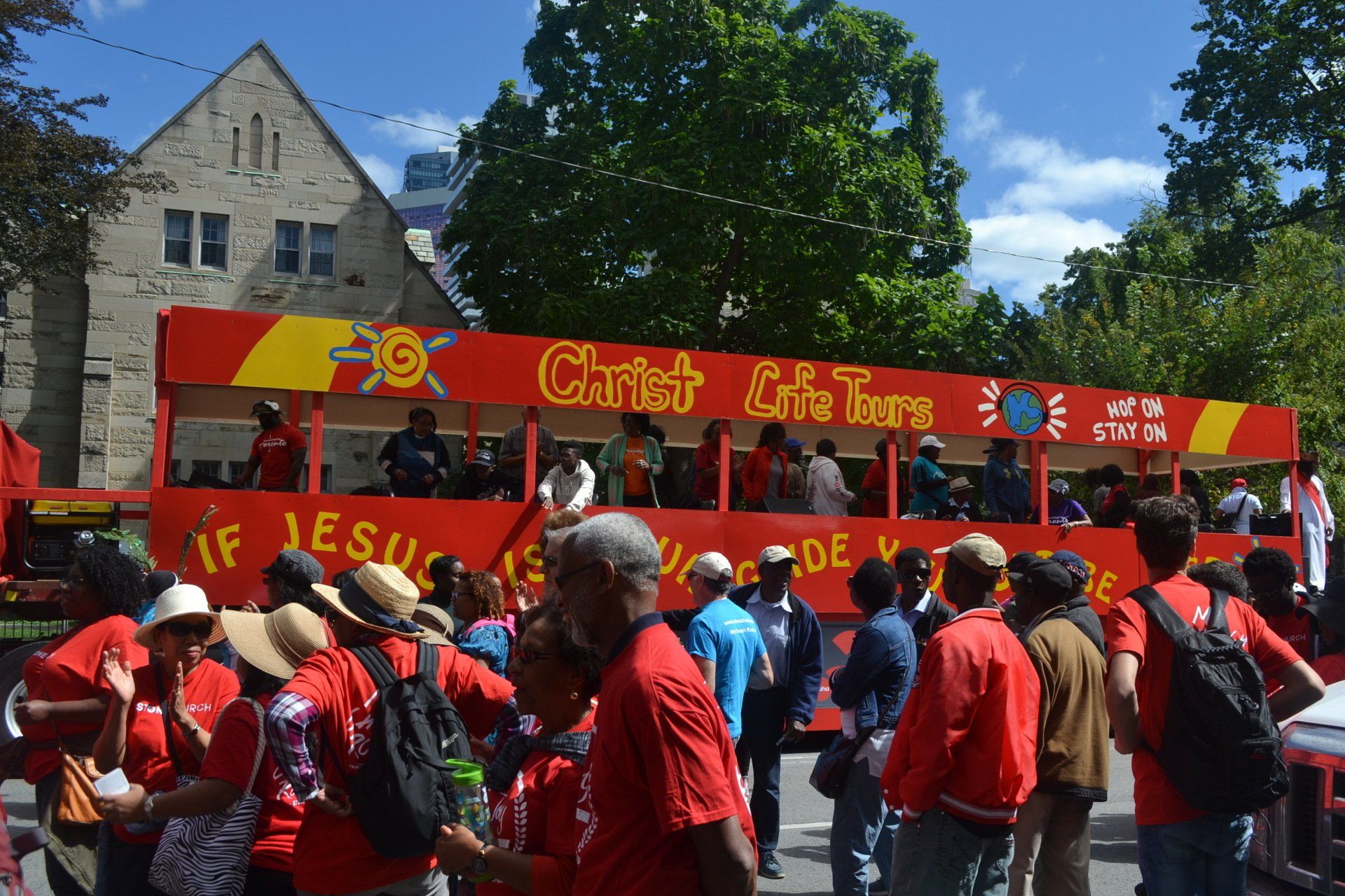 A group of people are standing in front of a red bus that says christ life tour