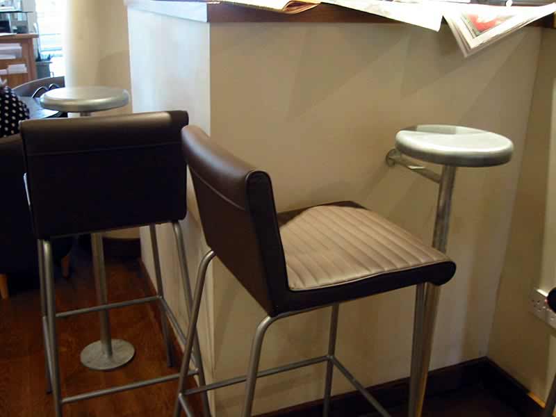 Two bar stools sit next to a counter with a newspaper on it