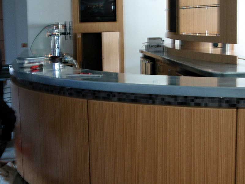 A kitchen with a curved counter top and wooden cabinets