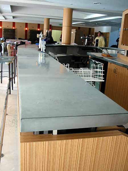 A kitchen with a concrete counter top and wooden cabinets