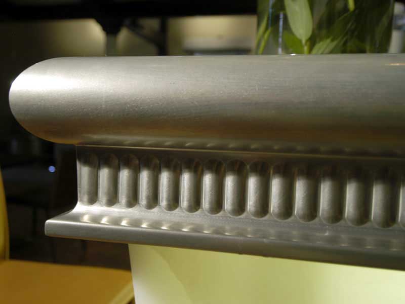 A vase of flowers sits on a table next to a metal railing.