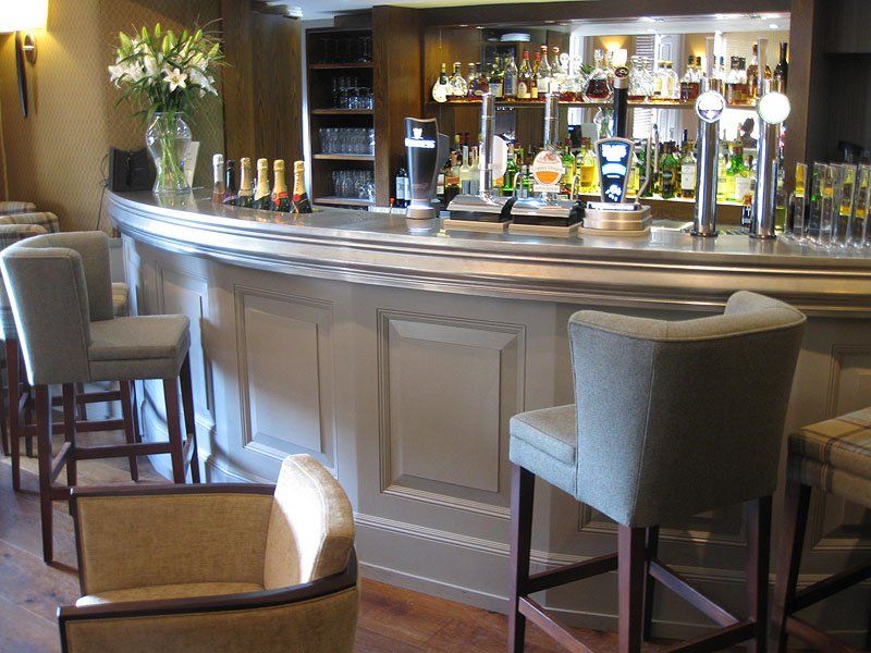 A bar with chairs and bottles of liquor on it