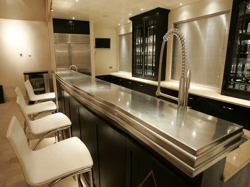 A kitchen with stainless steel counter tops and white chairs