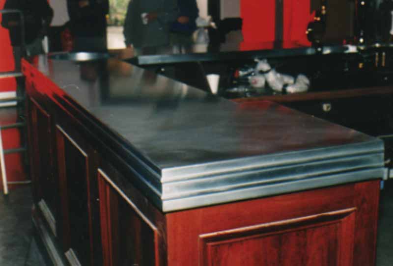 A bar with a stainless steel counter top and wooden cabinets