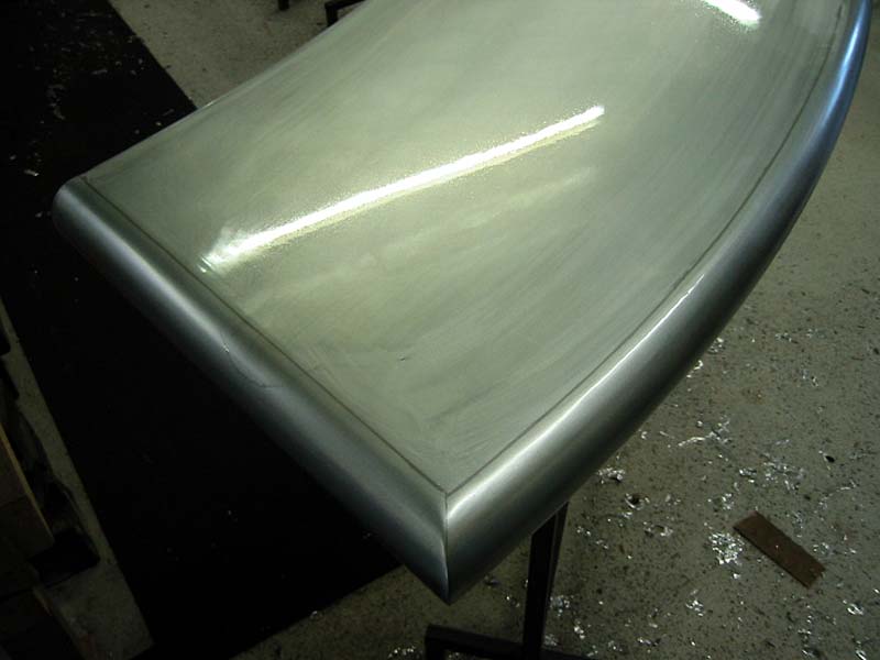 A stainless steel table with a curved edge is sitting on a table.