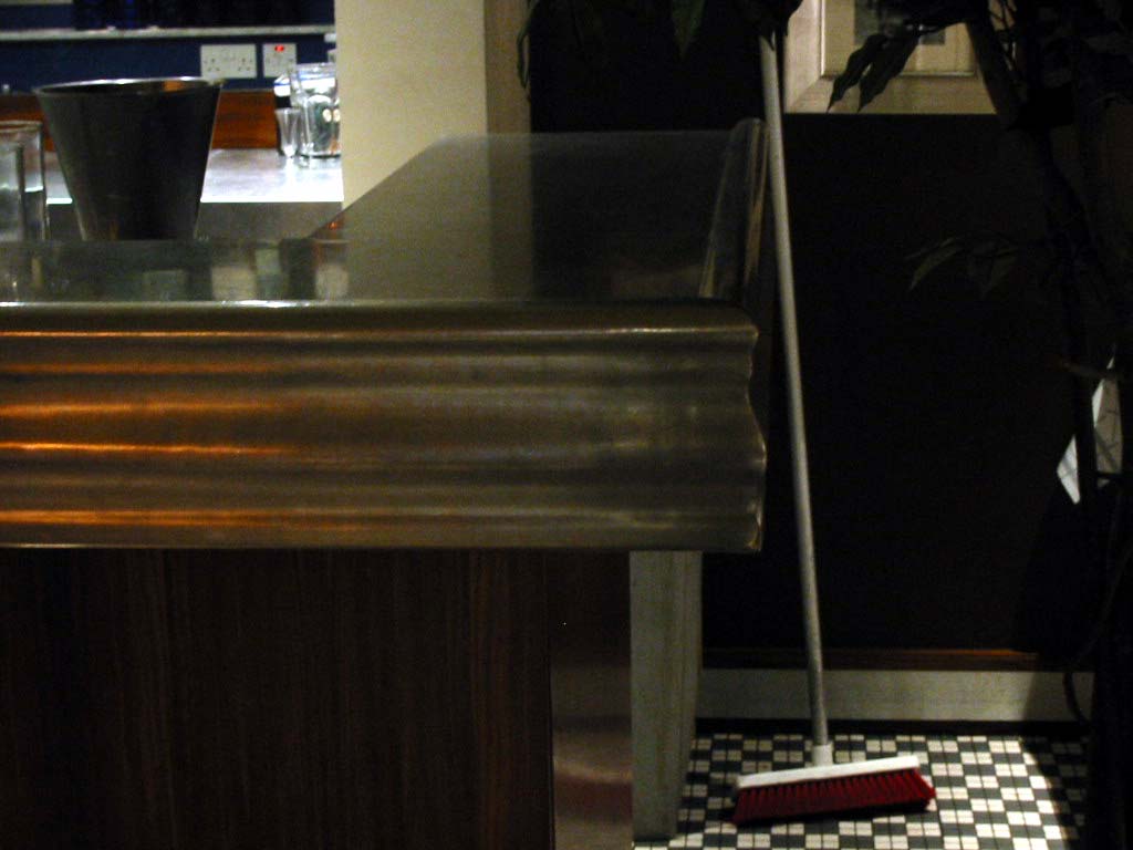 A broom is sitting on a checkered floor next to a counter