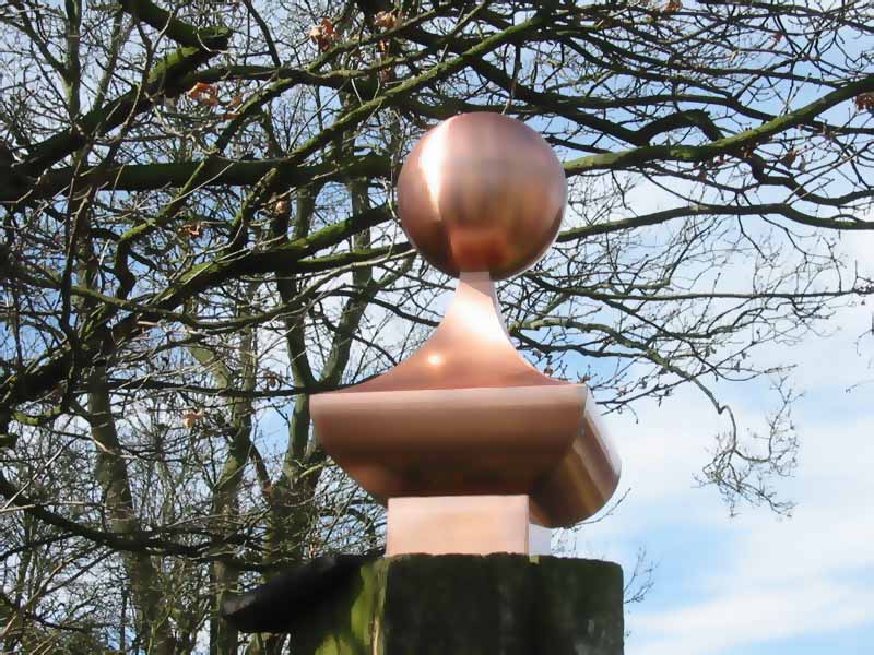 A copper ball on top of a wooden post