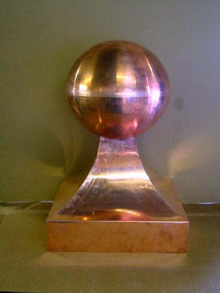 A copper ball on top of a wooden base