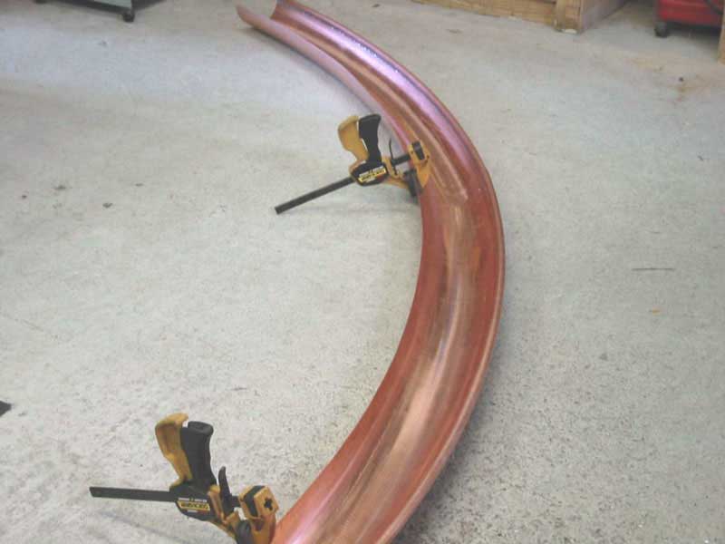 A curved piece of metal is being held together with clamps