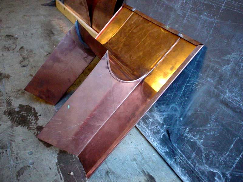 A pair of copper gutters are sitting on the ground