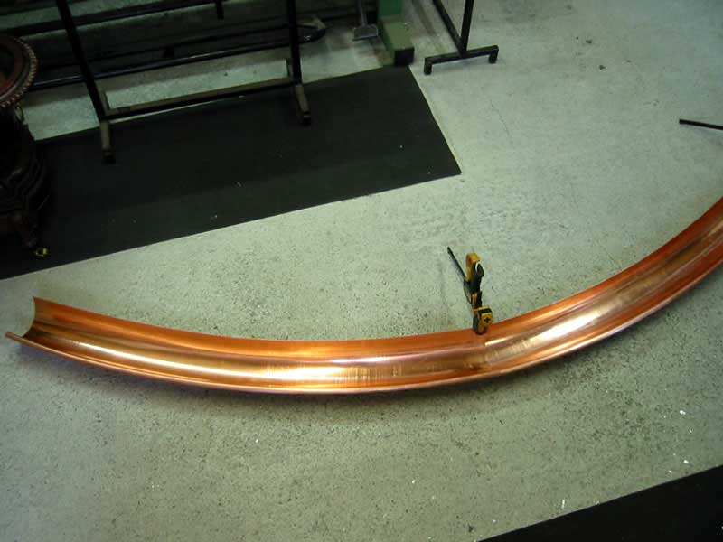 A curved piece of copper is sitting on the floor