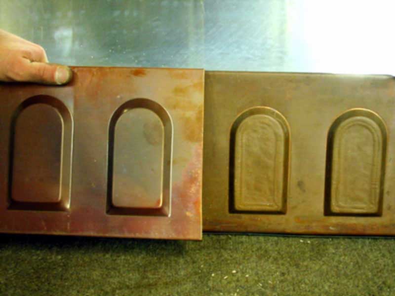 A person is holding a piece of wood with arches on it.