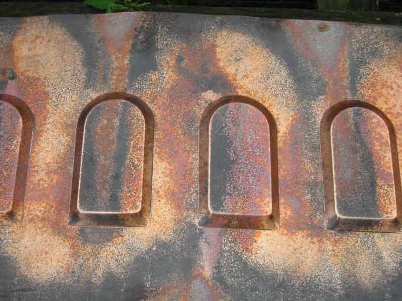 A close up of a rusty metal surface with arches carved into it