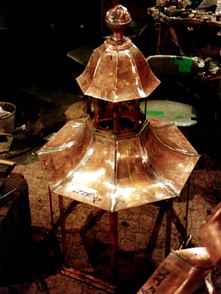 A copper sculpture is sitting on a table in a dark room