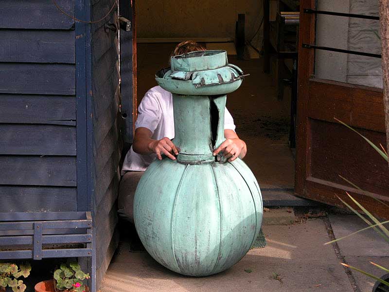 A man is sitting next to a large green vase