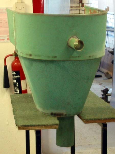 A green cone is sitting on a table next to a red fire extinguisher