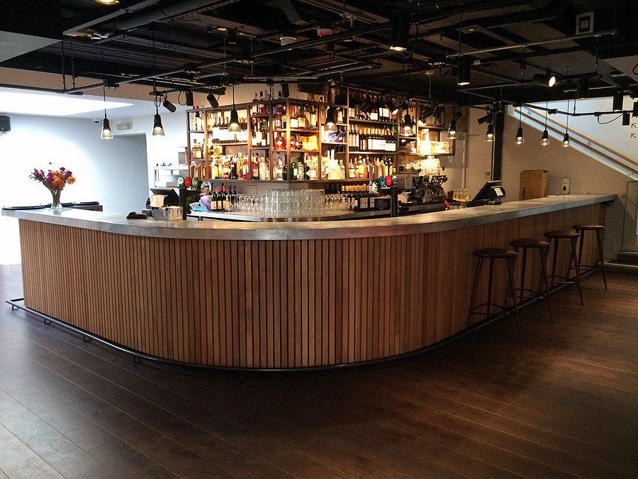 A bar with a wooden counter and stools in a restaurant