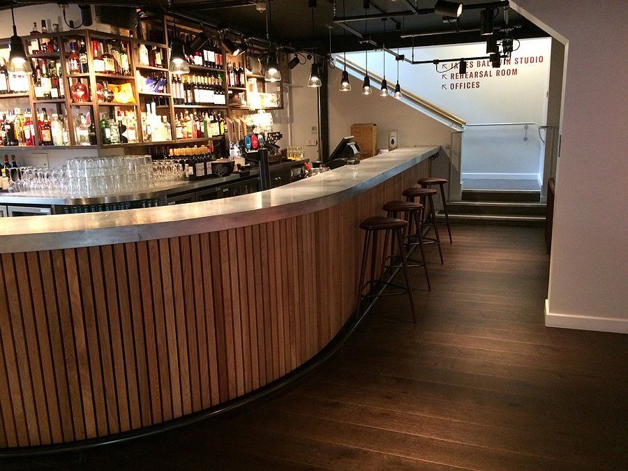 A bar with a wooden counter and stools in a restaurant