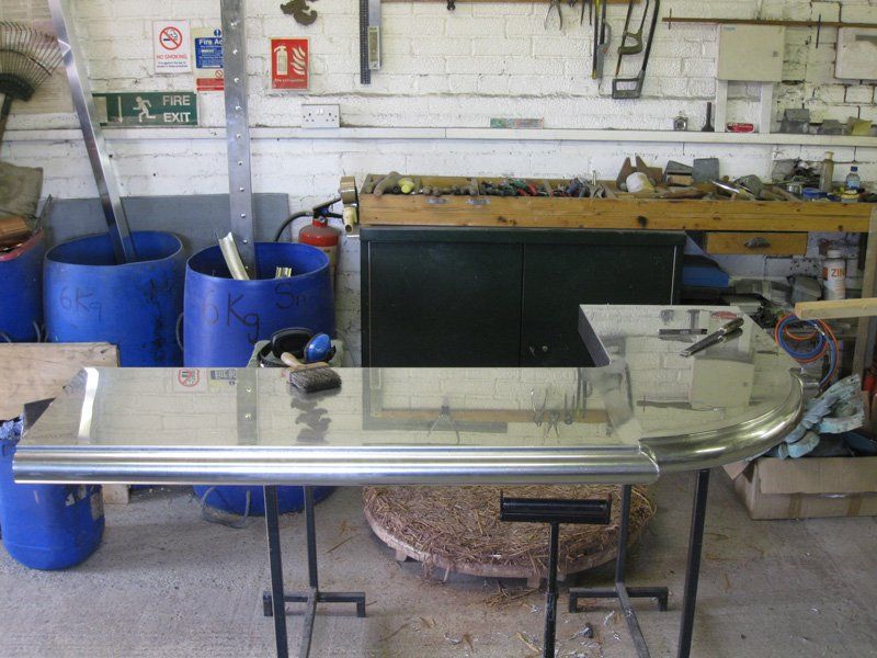 A stainless steel table in a workshop with a fire exit sign in the background