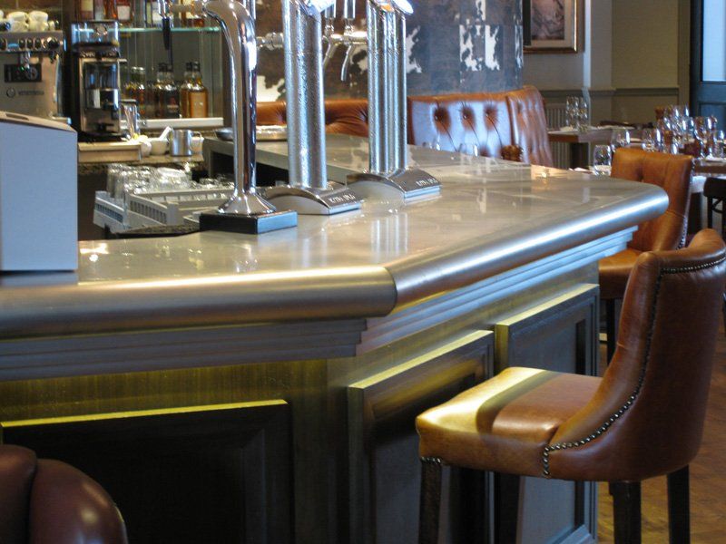 A bar in a restaurant with a few chairs