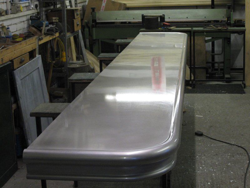 A long stainless steel counter top is sitting in a workshop.