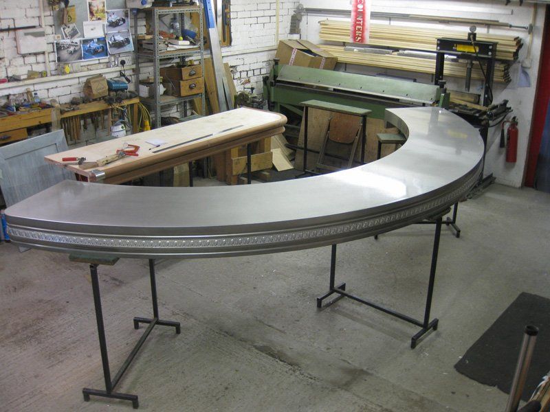 A large curved metal table is in a workshop