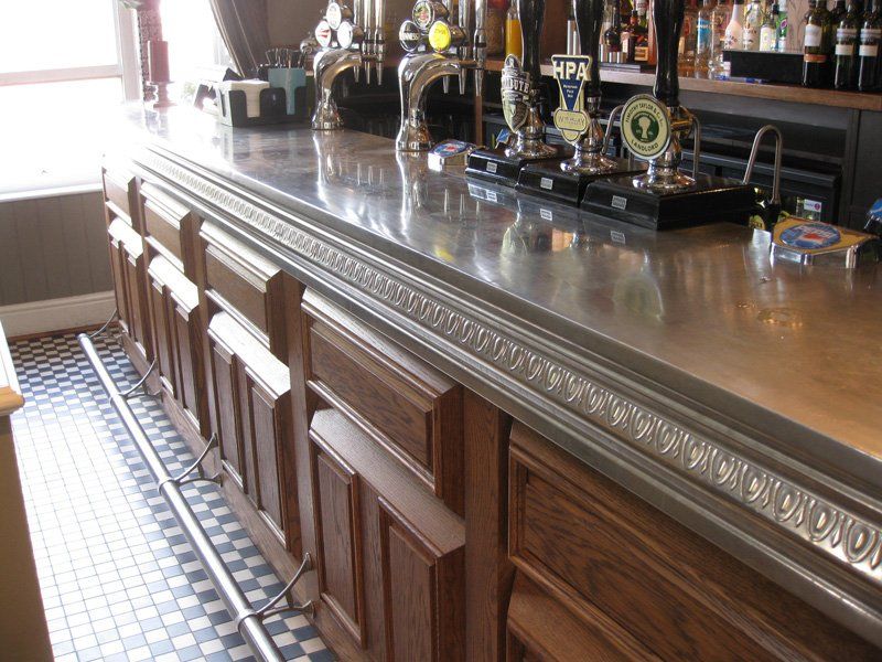 A bar with wooden cabinets and a stainless steel counter top