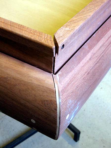A corner of a wooden table with a hole in it