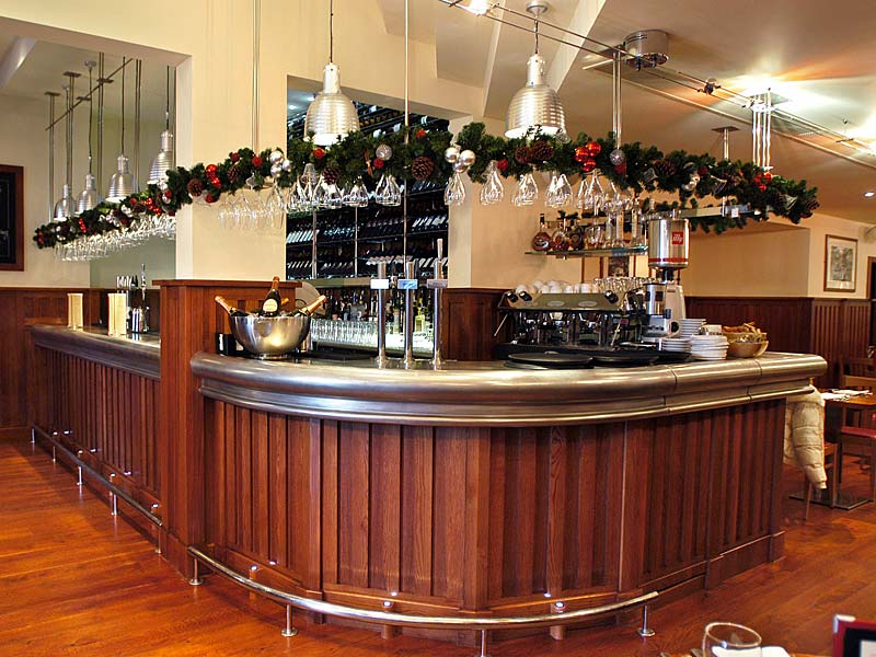 A long wooden bar in a restaurant decorated for christmas