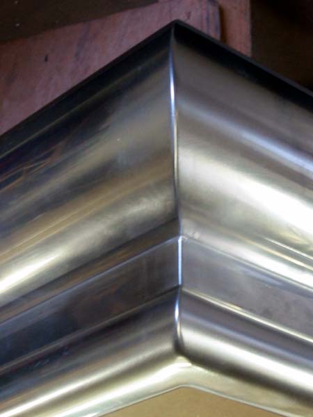 A close up of a stainless steel gutter on a ceiling.