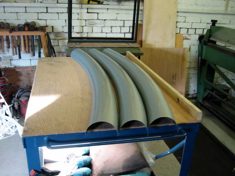 Three pieces of metal are sitting on a wooden table