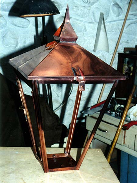 A copper lantern is sitting on a wooden table