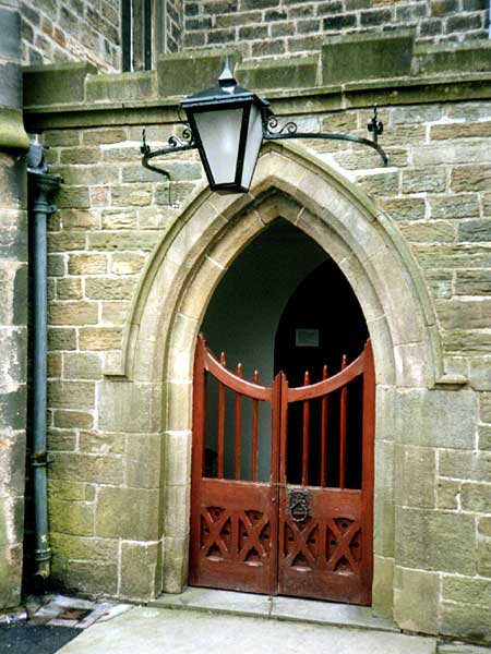 A brick building with a red door and a lamp above it