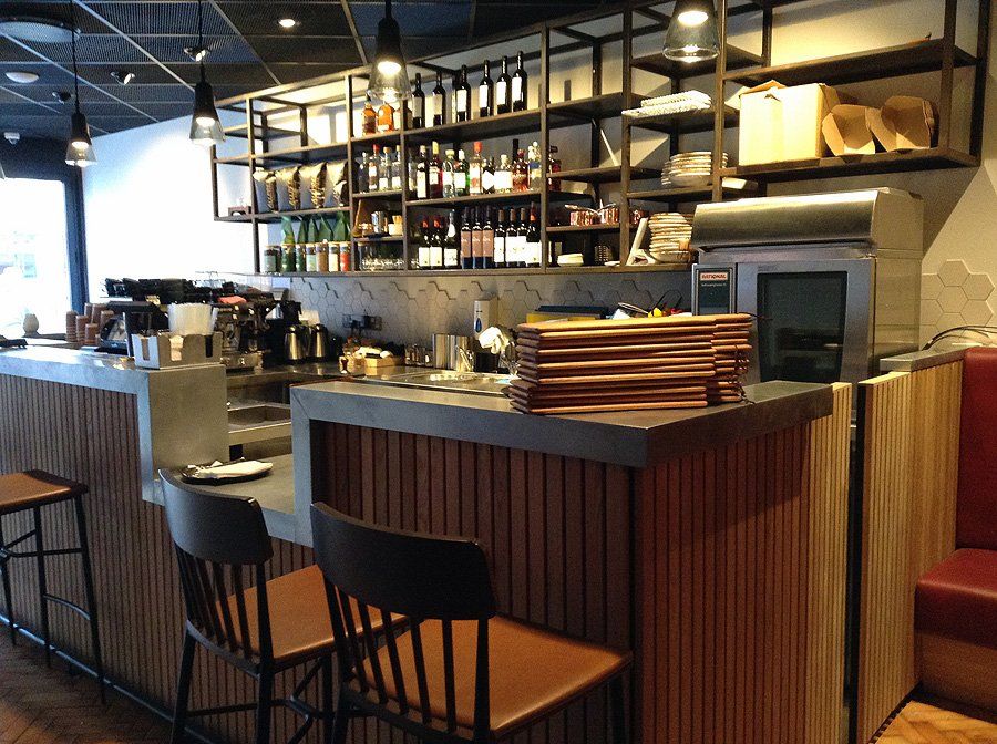 A bar in a restaurant with a stack of plates on top of it