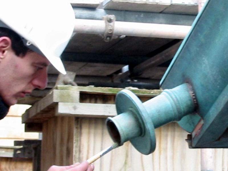 A man wearing a hard hat is working on a piece of metal