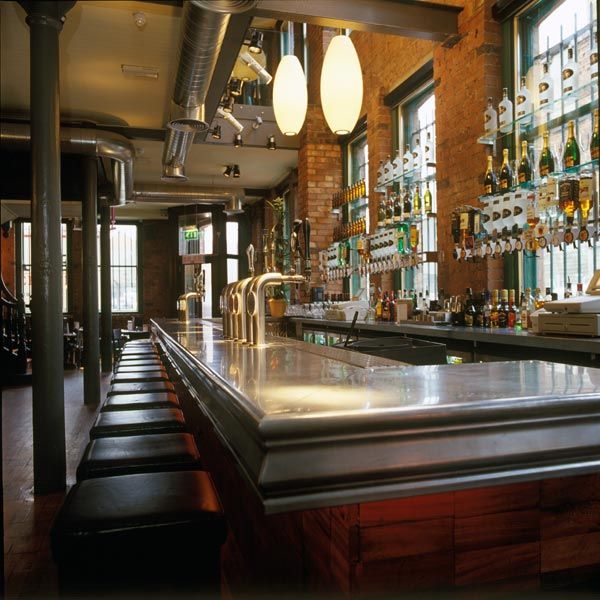 A long bar in a restaurant with many bottles on shelves