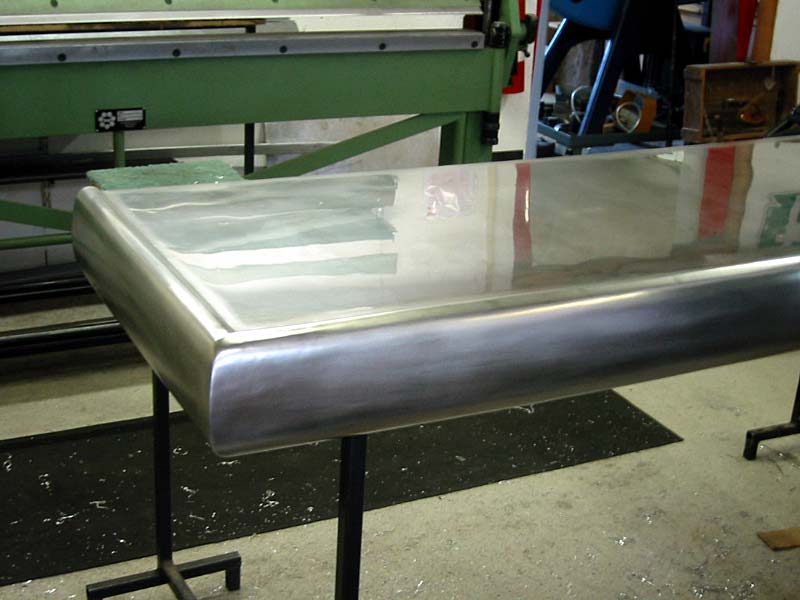 A stainless steel table with a green machine in the background