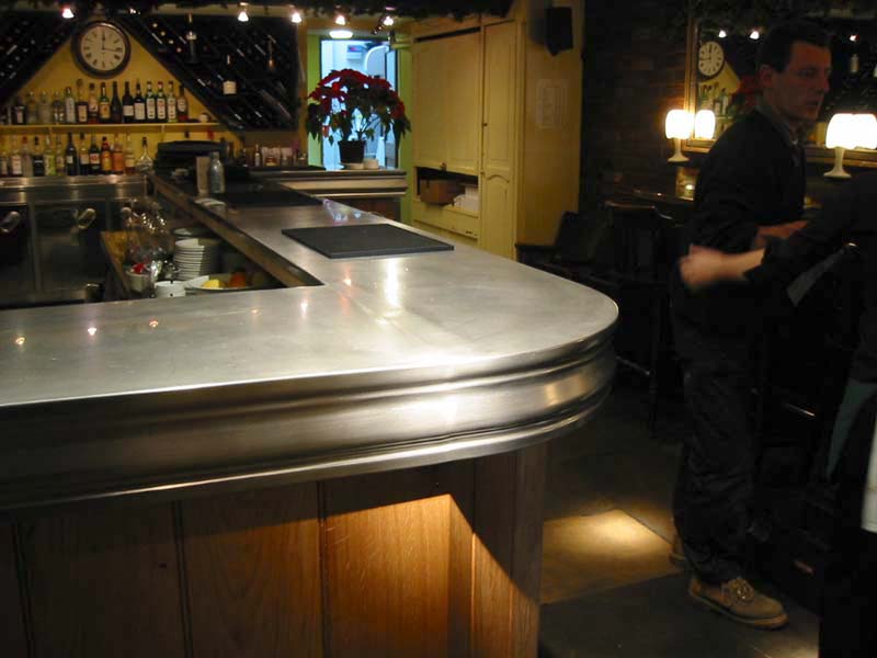 A man standing at a bar with a clock on the wall