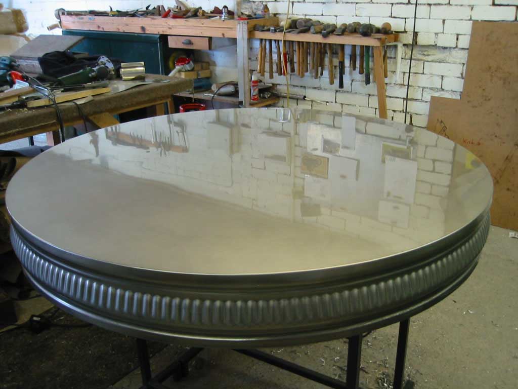 A round metal table with a brick wall in the background