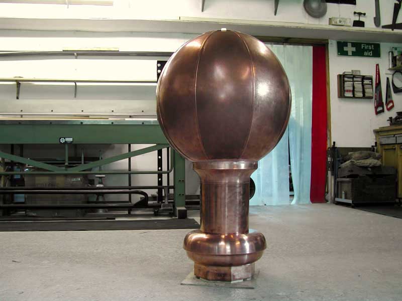 A large copper ball is sitting on the floor in a room