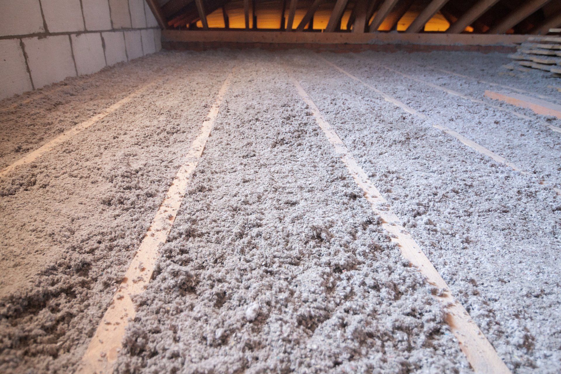 Insulated attic floor with blown-in white insulation and exposed roof beams