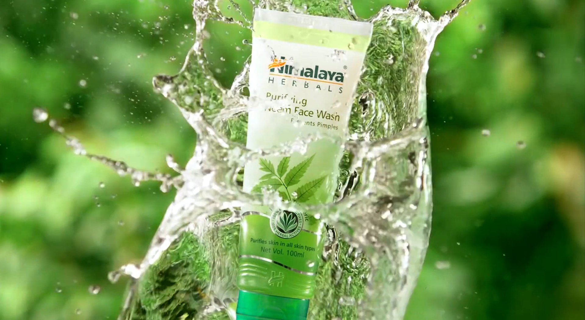Green skincare tube splashing through water against a blurred green background