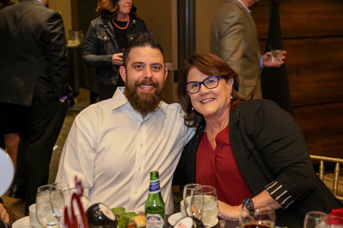 A man and a woman are posing for a picture at a table at a party.
